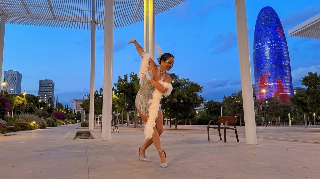Una de las bailarinas de Las Coquettes en pose frente a la Torre Glòries iluminada, en el parque de Les Glòries de Barcelona.